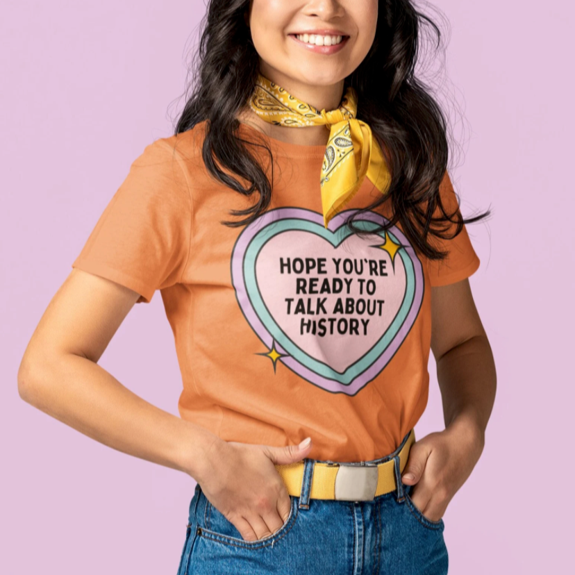 Woman wearing a t-shirt with a heart graphic and text, standing against a light purple background