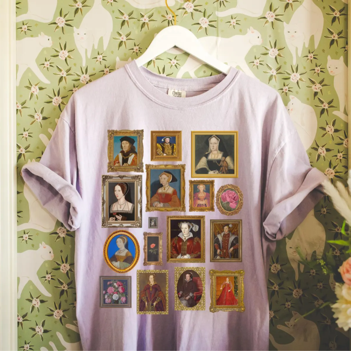 Light purple t-shirt with vintage tudor history portrait collage on a hanger against a floral wallpaper background.